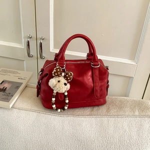 Close-up of bright red vintage Boston bag featuring a plush dog charm and pearl beads