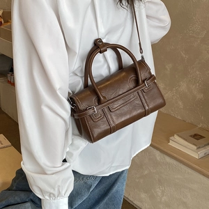 Detail of a dark brown vintage satchel bag with glossy faux leather and white stitching