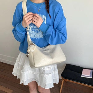 Détail du sac hobo blanc crème plissé avec bandoulière large et charm d'agneau en peluche
