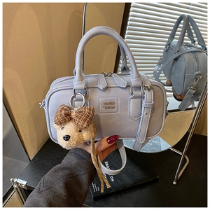 Detail of light blue Boston bag with plush bear charm and silver hardware shown in mirror