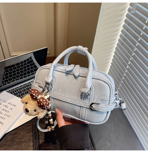 Détail d'un sac à main bleu clair en similicuir avec boucle et pendentif ours