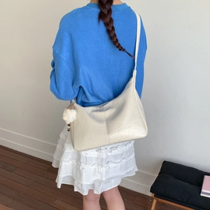 Détail du sac hobo blanc crème montrant le cuir souple et le pendentif en peluche