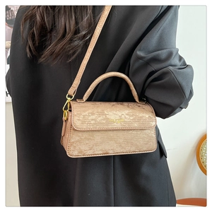 Detail of champagne gold handbag with horizontal texture and adjustable shoulder strap