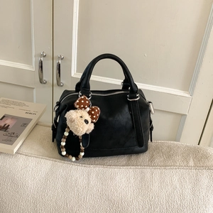 Detail of black matte synthetic leather Boston bag with a cute puppy plush charm