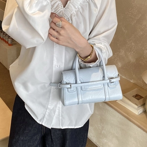 Detail shot of light blue flap handbag with decorative buckle in a lifestyle setting