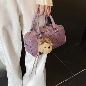 Detail of purple Boston handbag with silver hardware and plush bear charm on strap