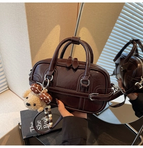 Détail du sac Boston marron café brillant avec breloque chiot en peluche et double anses