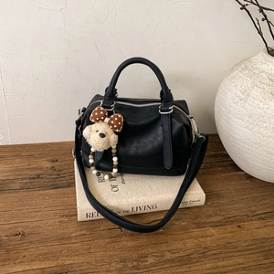 Vintage black leather Boston bag with plush puppy charm and adjustable shoulder strap