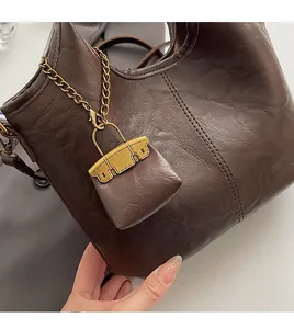 Détail du sac seau rétro en cuir marron avec chaîne en métal et mini pochette