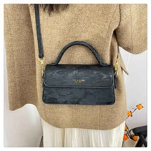 Chic black textured crossbody bag featuring gold hardware and elegant shoulder strap detail