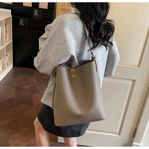 Detailed side view of taupe lychee texture bucket bag with a golden metal clasp