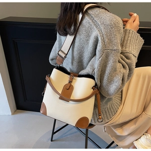 Close-up of contrast leather bucket bag with wide strap on a model for scale