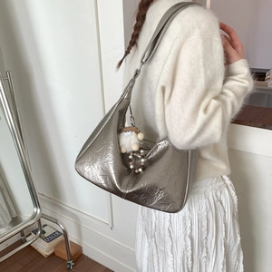 Détail d'un sac hobo argenté métallisé avec breloque en peluche blanche et perles déco