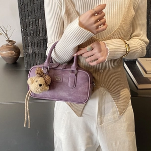 Detail of purple matte pillow bag with bear charm and metallic handle hardware