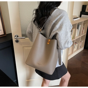 Detail view of the gray leather bucket bag with a golden metal twist-lock and fashion stamp
