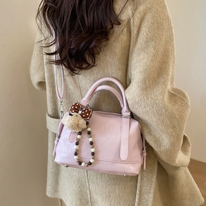Close-up of pink leather tote bag with cute bear charm and polka dot bow detail