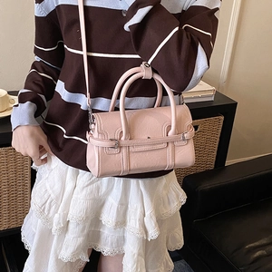 Detail of pink PU leather handbag showing fine texture and vintage buckle straps