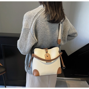 Detail view of cream bucket bag with brown lychee pattern trim and wide shoulder strap