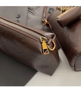 Gros plan sur la fermeture éclair dorée et la texture en cuir marron du sac à main