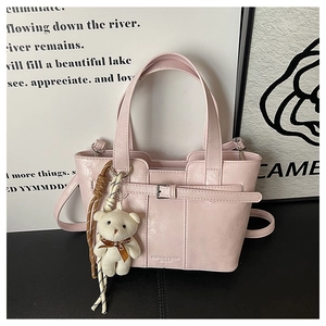 Detail of light pink bucket bag with PU leather texture and cute white bear keychain
