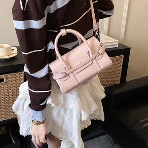 Detail view of pink crossbody bag with round handles and adjustable strap on a model