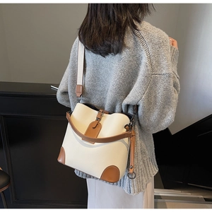 Detailed view of cream and brown bucket bag with wide canvas strap on model