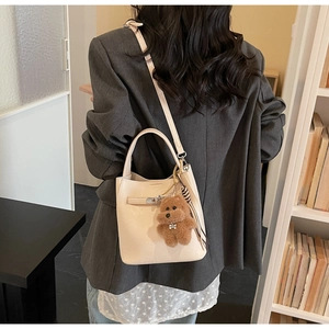 Chic cream white bucket bag shown on model with cute brown plush bear charm detail