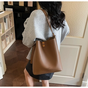 Detailed view of the brown lychee grain leather bucket bag with metallic twist lock closure