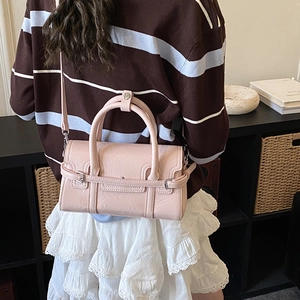 Detailed close-up of light pink leather handbag featuring silver hardware and fine texture