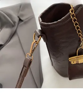 Détail du sac seau en cuir marron vintage avec crochets dorés et finition cuir ciré texturé