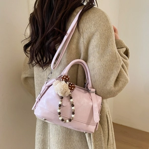 Detail of light pink Boston bag with cute teddy bear charm and beaded bow accessory