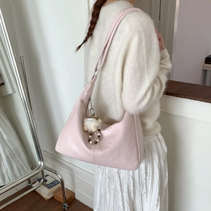 Détail du sac hobo rose brillant avec charme en peluche porté par un mannequin en intérieur