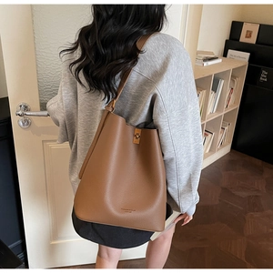 Detailed view of brown lychee grain leather bucket bag with gold metal twist lock and logo