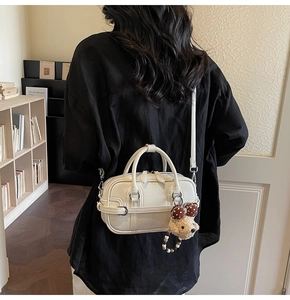 Vue détaillée du mini sac Boston blanc crème avec charm ourson et nœud papillon à pois