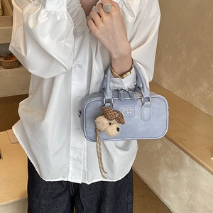 Detail of light blue Boston bag with embossed logo and cute puppy plush pendant charm