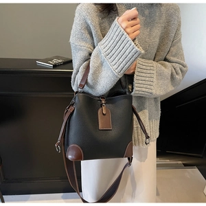 Detail view of the contrast litchi leather texture and brown handle on a vintage bucket bag