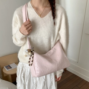 Détail du sac à bandoulière rose plissé avec texture douce et breloque poupée mignonne
