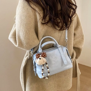 Detail showing a light blue Boston bag with a cute teddy bear charm and strap