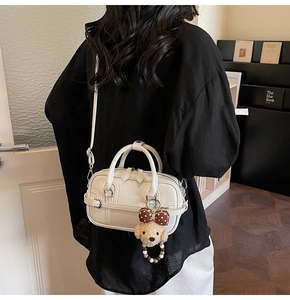 Sac Boston beige chic avec un charme d'ours montré dans un cadre de vie douillet