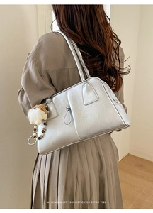 Silver metallic shoulder bag with plush charm shown in a lifestyle street style back view