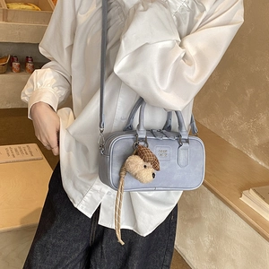 Lifestyle shot of light blue Boston bag with plush dog charm and adjustable shoulder strap