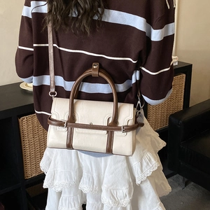 Detail view of cream and brown crossbody bag shown with adjustable shoulder strap
