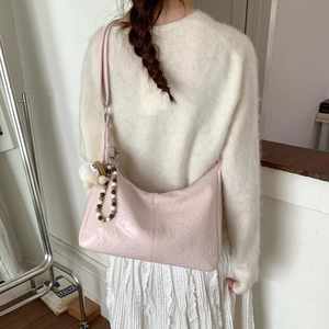 Détail du sac à bandoulière rose clair en similicuir froissé avec breloque en peluche