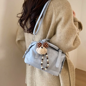 Detail view of light blue leather tote bag with cute plush puppy charm on a wool coat