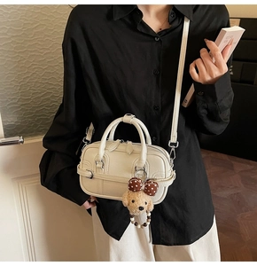 Détail du sac Boston crème avec charm ours en peluche porté par un mannequin