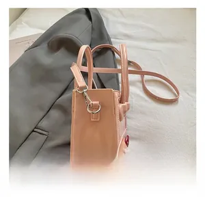 Detail shot of pink patent leather small handbag with silver metal hardware and straps
