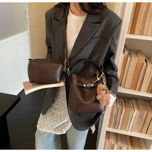 Detail of deep brown bucket bag set with texture and plush bear charm decoration