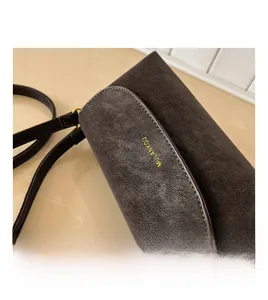 Gros plan d'un sac bandoulière marron mat avec logo doré et surpiqûres décoratives