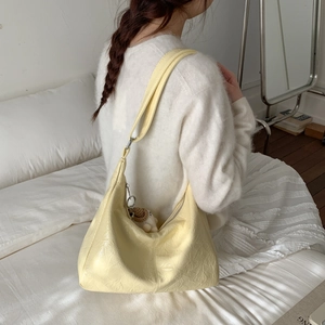 Vue détaillée d'un sac à bandoulière plissé jaune crème avec un pendentif ours mignon