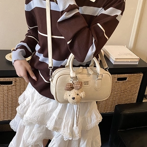 Detail of beige leather Boston bag with teddy bear charm and embossed logo design